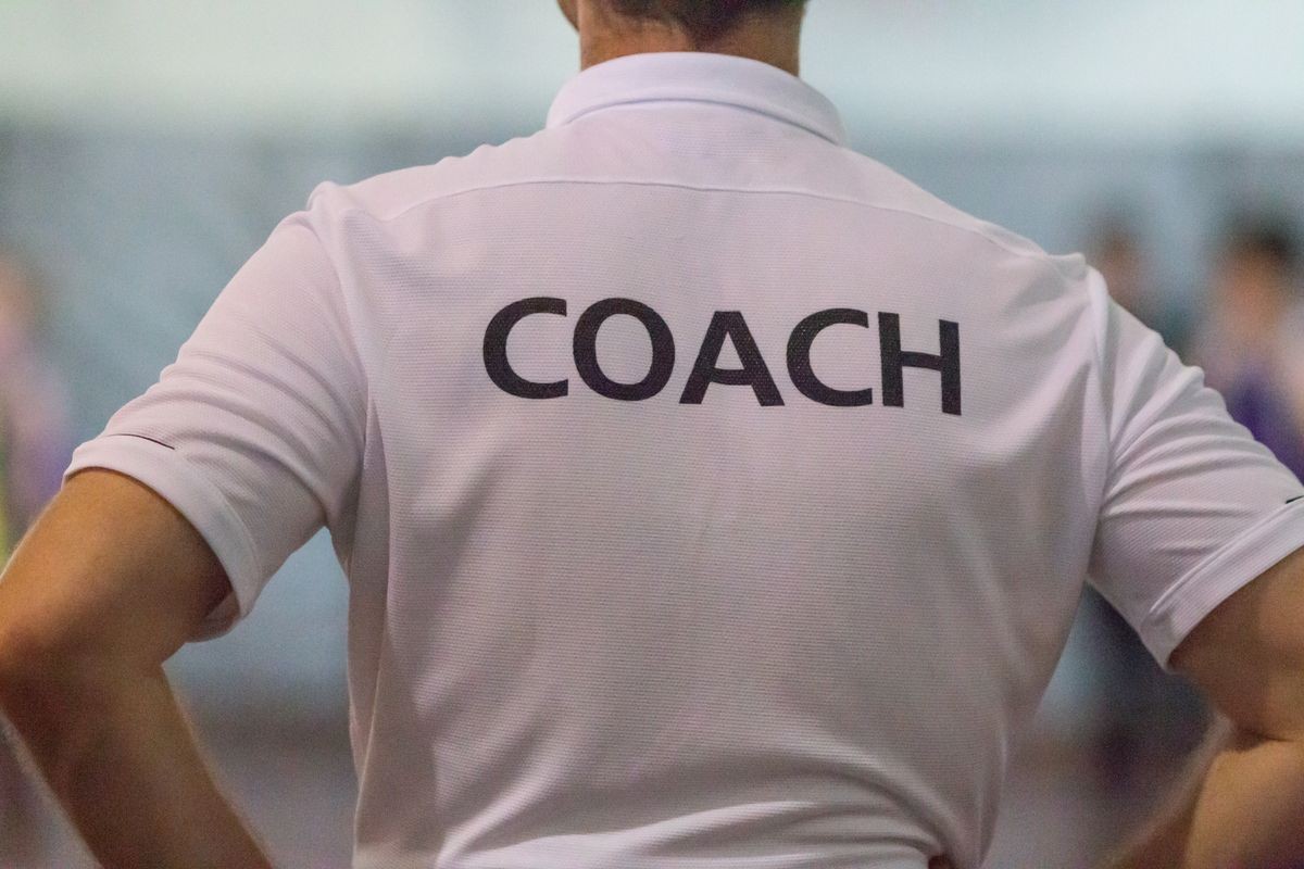 Back view of male sport coach with word COACH written on back of his shirt